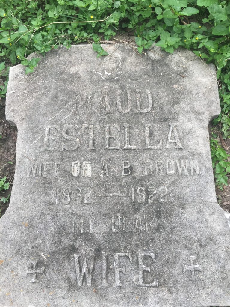 Gray headstone reads: "Maud Estella; wife of A. B. Brown;" the years are hard to make out. At the bottom it says "WIFE" in big letters.